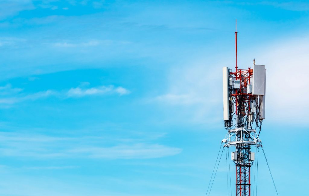 Telecommunication tower with blue sky and white clouds background. Antenna on blue sky. Radio and sa